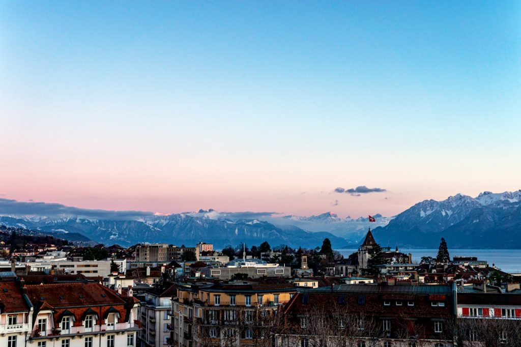 Breathtaking sunset view of Lausanne cityscape with Alps and Lake Geneva in the backdrop.